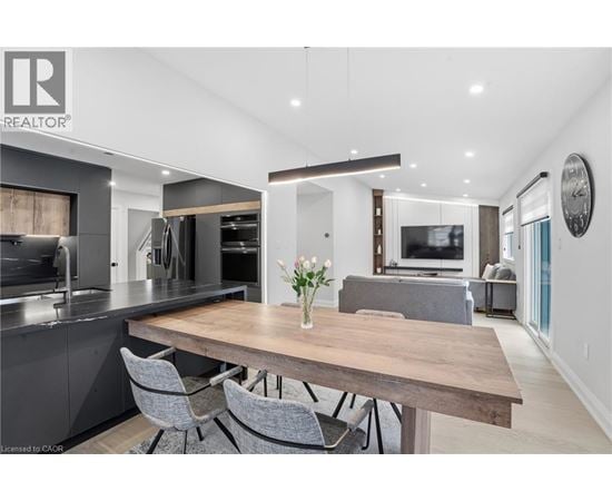 A modern kitchen with a wooden table and grey chairs.