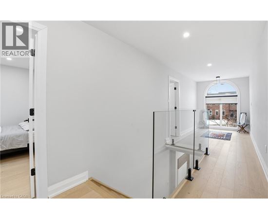 A white bedroom with a glass door leading to a balcony.