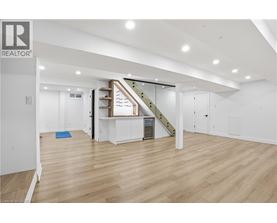 A spacious room with wooden flooring and a staircase leading to the upper level.
