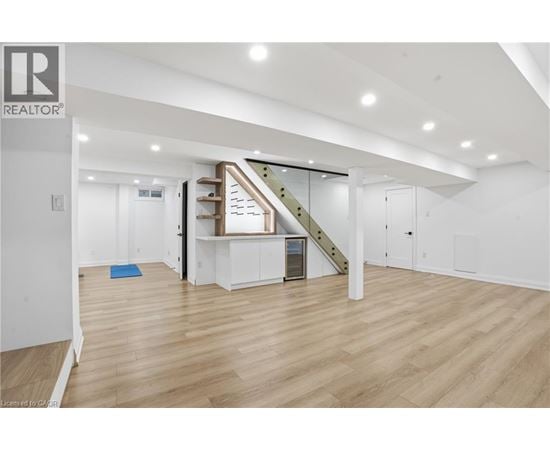 A spacious room with wooden flooring and a staircase leading to the upper level.