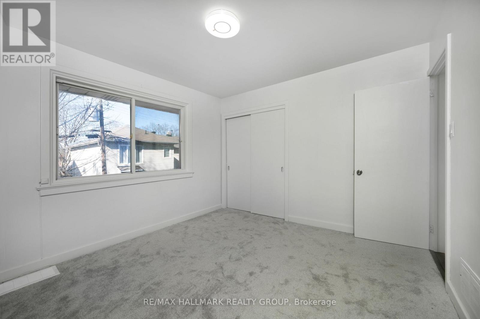 A white bedroom with a window and a carpeted floor.