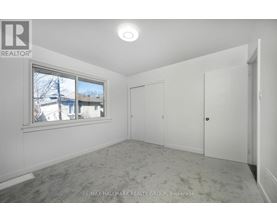 A white bedroom with a window and a carpeted floor.