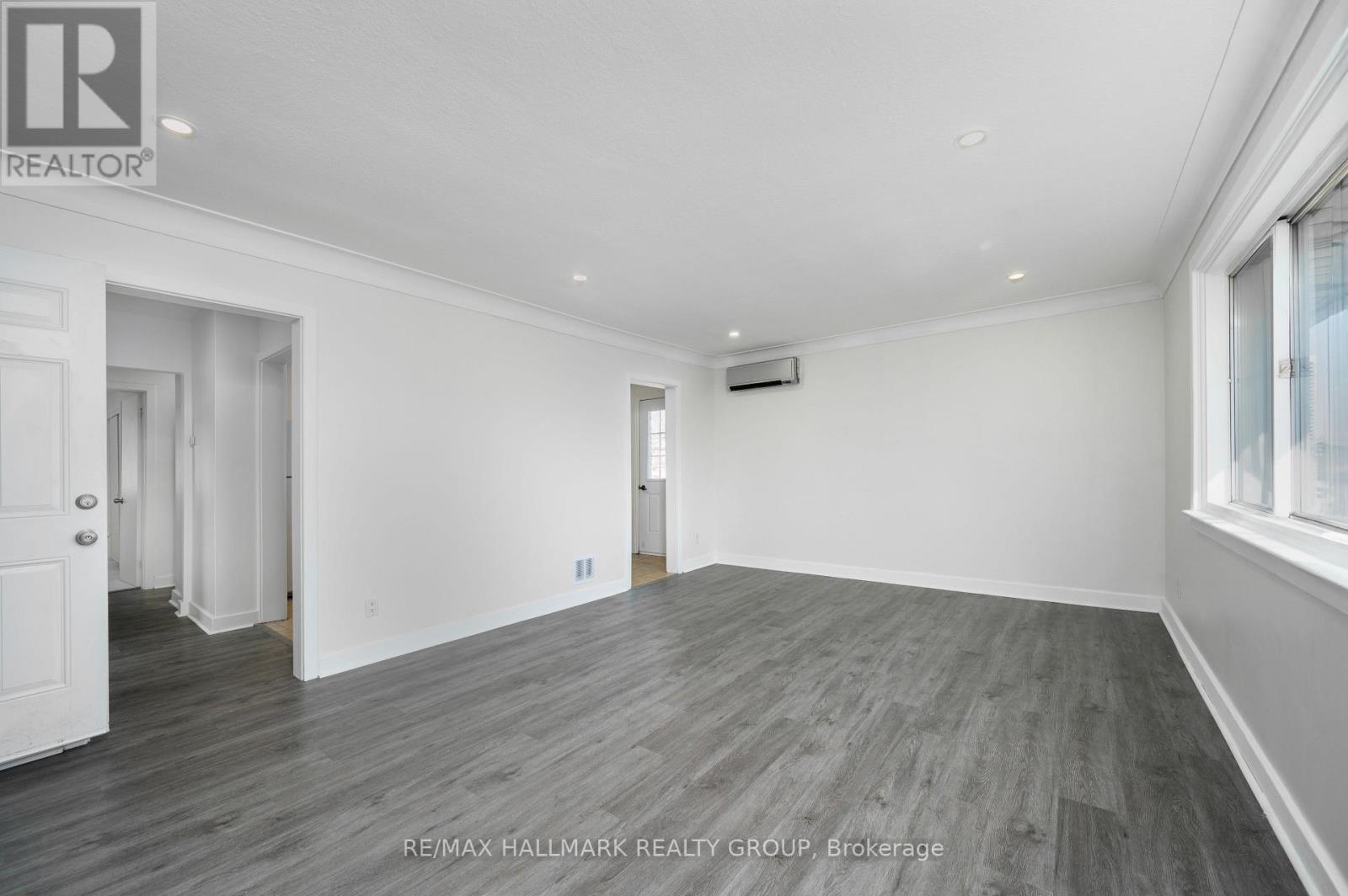 A spacious room with wooden flooring and white walls.