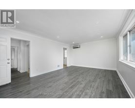 A spacious room with wooden flooring and white walls.