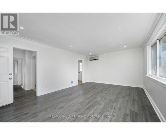 A spacious room with wooden flooring and white walls.