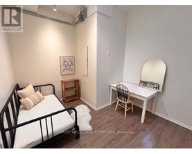 A bedroom with a bed, chair, and a mirror.