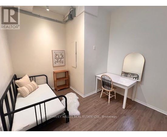 A bedroom with a bed, chair, and a mirror.