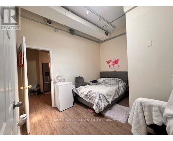 A bedroom with a bed, nightstand, and a wall-mounted air conditioner unit.