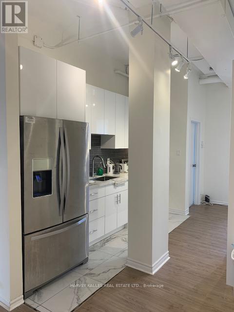 A modern kitchen with a stainless steel refrigerator and white cabinets.