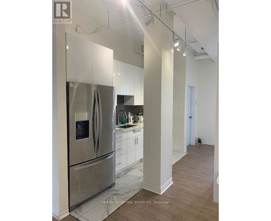 A modern kitchen with a stainless steel refrigerator and white cabinets.