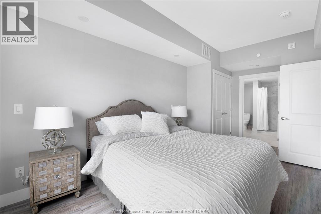 A bedroom with a large bed and a nightstand with a lamp.
