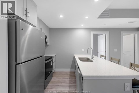 A modern kitchen with a stainless steel refrigerator and a white countertop.