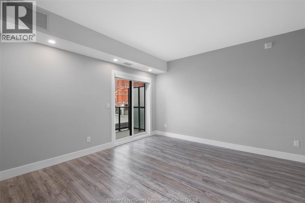 A spacious room with a wooden floor and a glass door leading to a balcony.