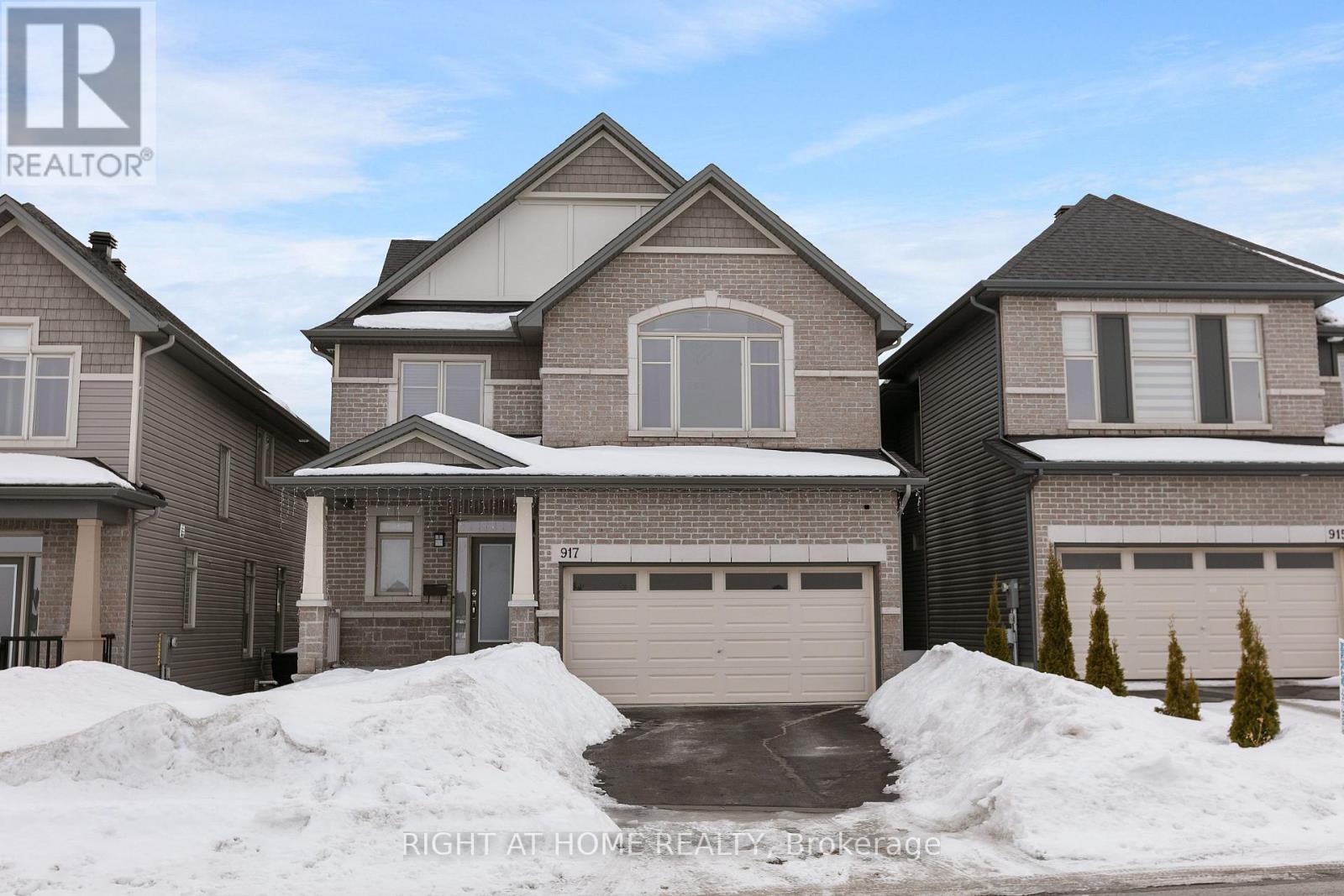 A large house with a garage is surrounded by snow.