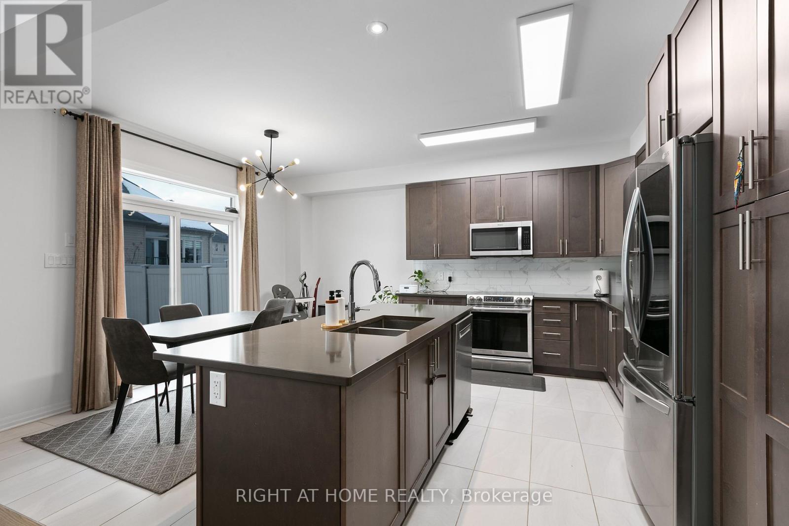 A modern kitchen with dark brown cabinets and stainless steel appliances.