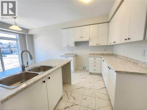 A kitchen with white cabinets and marble countertops.