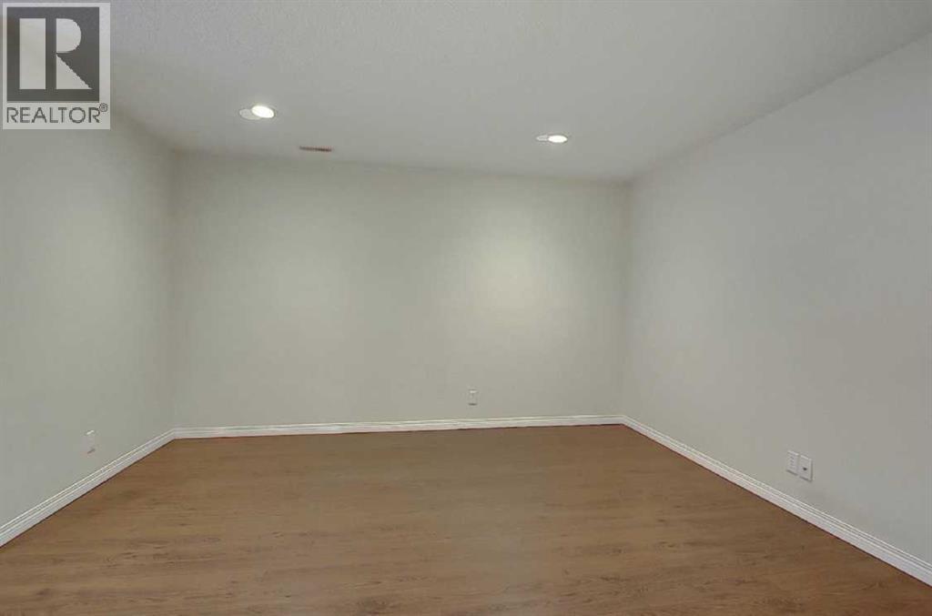A large empty room with wooden flooring and white walls.