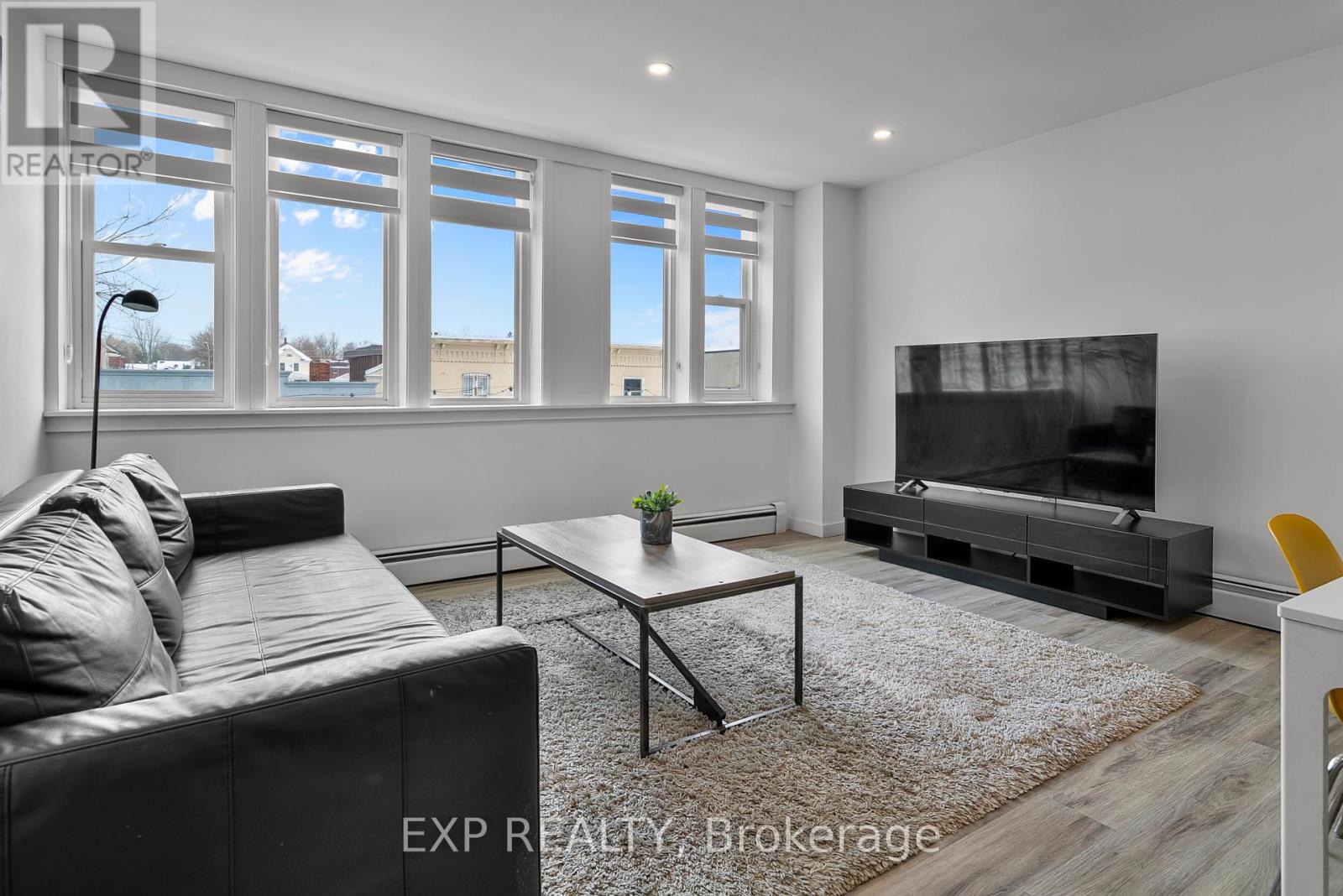 A living room with a black leather couch, a coffee table, and a flat screen TV.