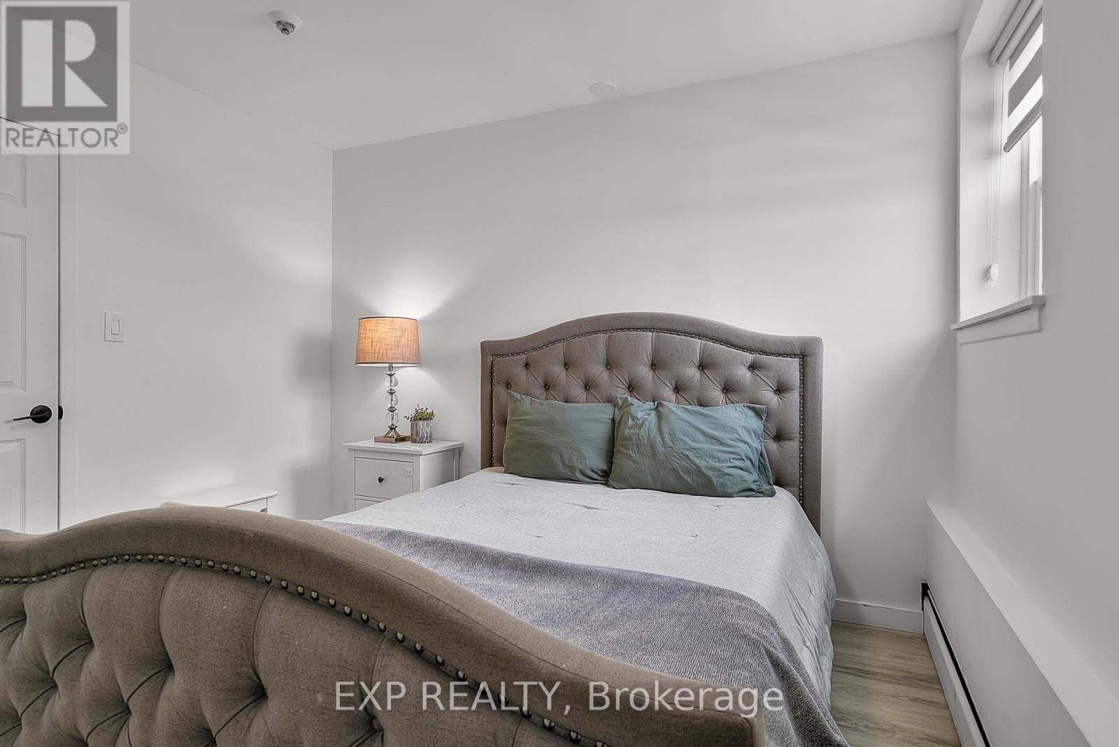 A bedroom with a tufted headboard and a bed with a grey blanket.