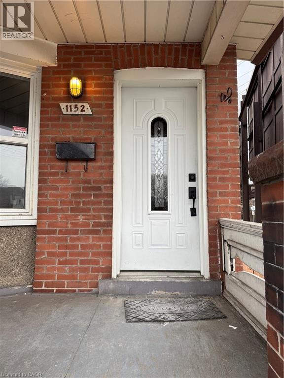 A white door with a glass panel is on the front of a brick building.