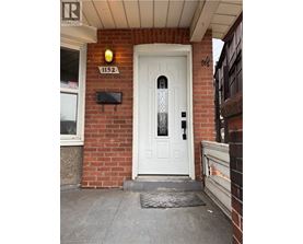 A white door with a glass panel is on the front of a brick building.