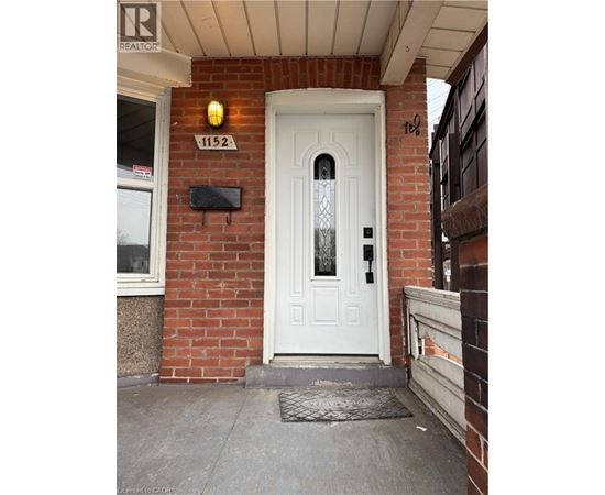 A white door with a glass panel is on the front of a brick building.