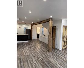 A spacious room with wooden floors and a large wooden beam on the ceiling.