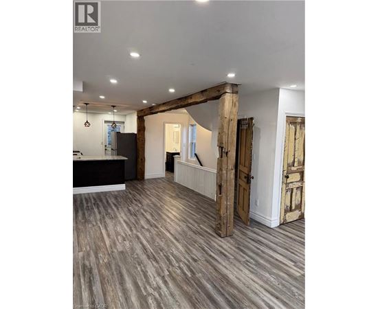 A spacious room with wooden floors and a large wooden beam on the ceiling.