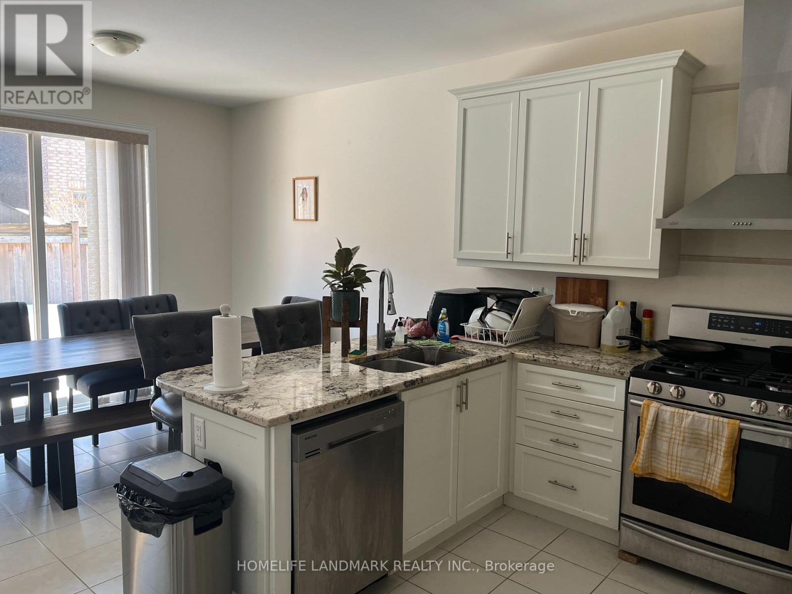 A kitchen with white cabinets and a marble countertop.