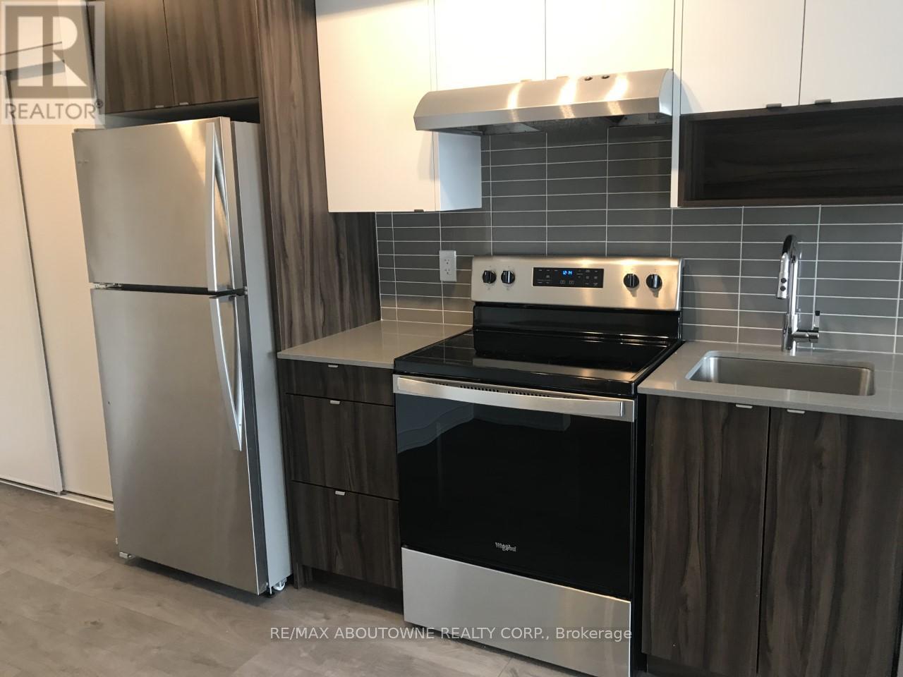 A modern kitchen with a stainless steel refrigerator, oven, and sink.