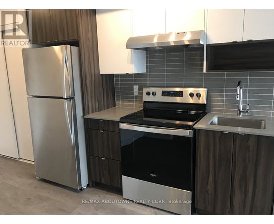 A modern kitchen with a stainless steel refrigerator, oven, and sink.