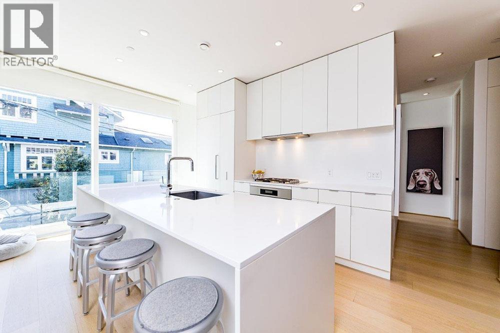 A modern kitchen with white cabinets and a bar area.