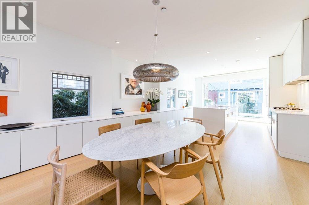 A modern dining room with a white table and chairs.