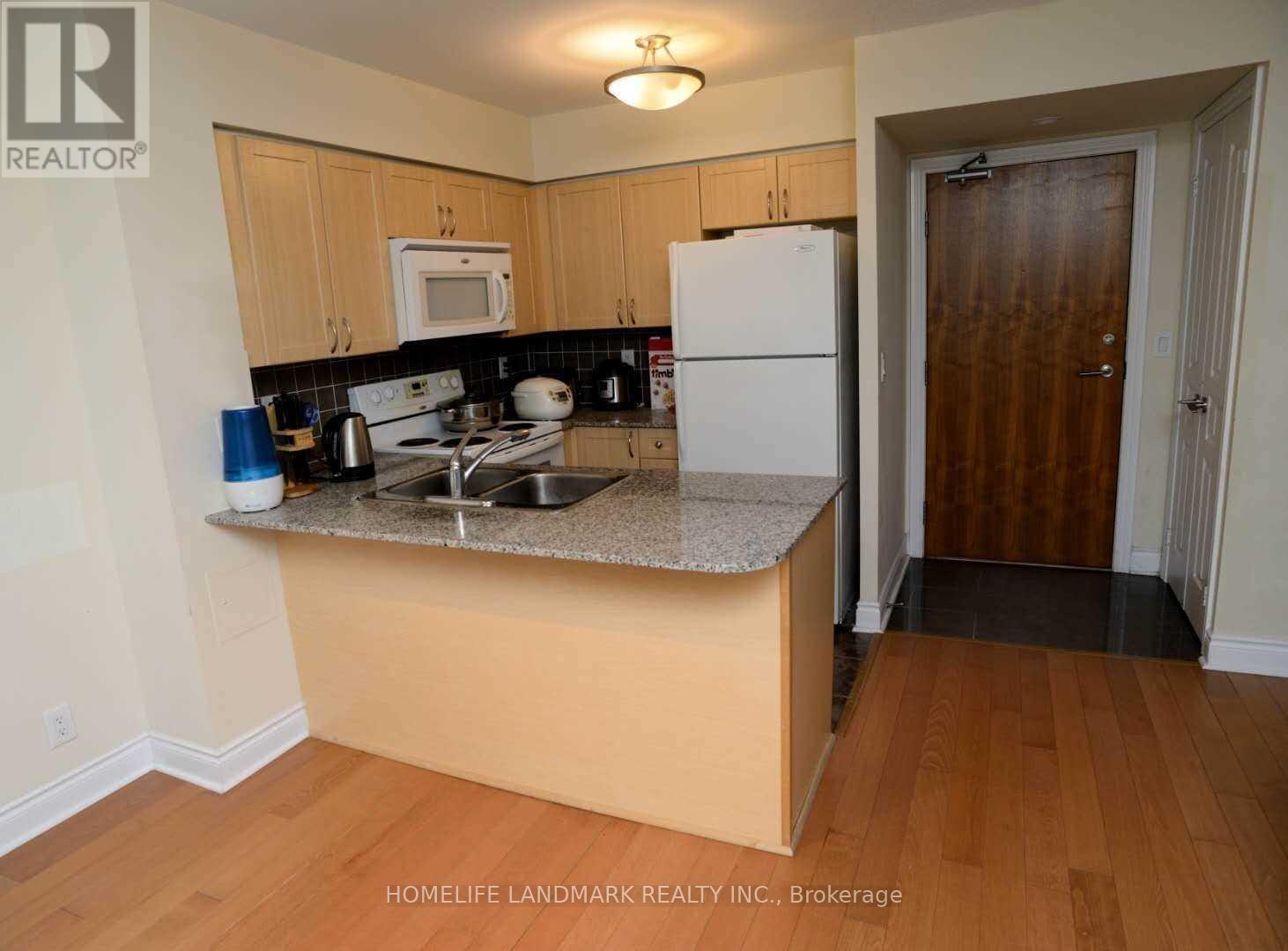A kitchen with a white refrigerator and wooden cabinets.