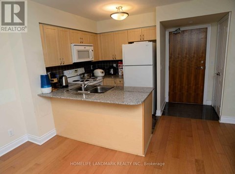 A kitchen with a white refrigerator and wooden cabinets.