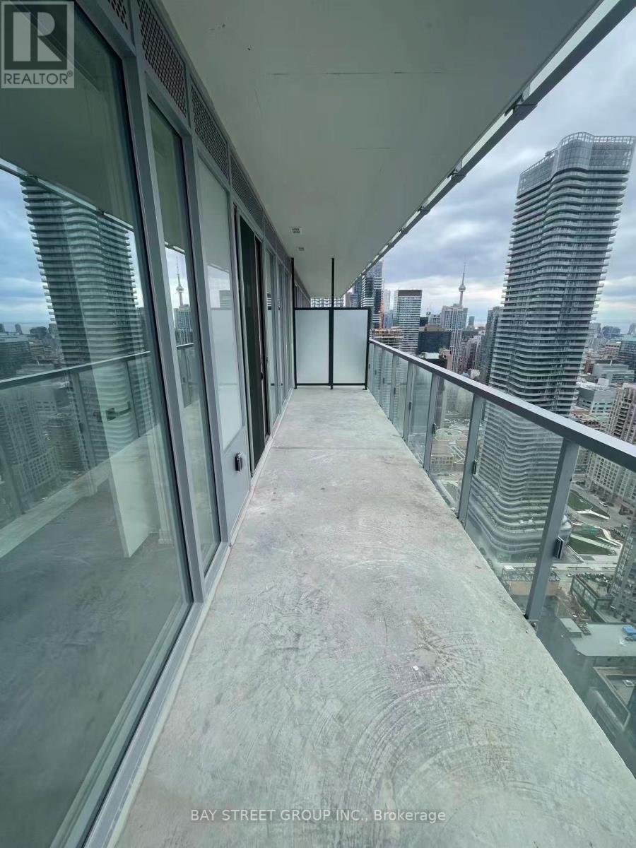 A balcony with glass doors and a view of the city.