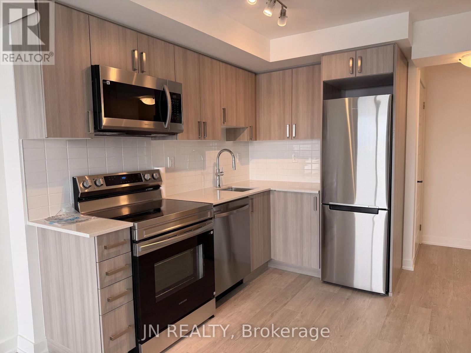 A modern kitchen with stainless steel appliances and wooden cabinets.