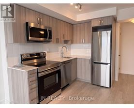 A modern kitchen with stainless steel appliances and wooden cabinets.