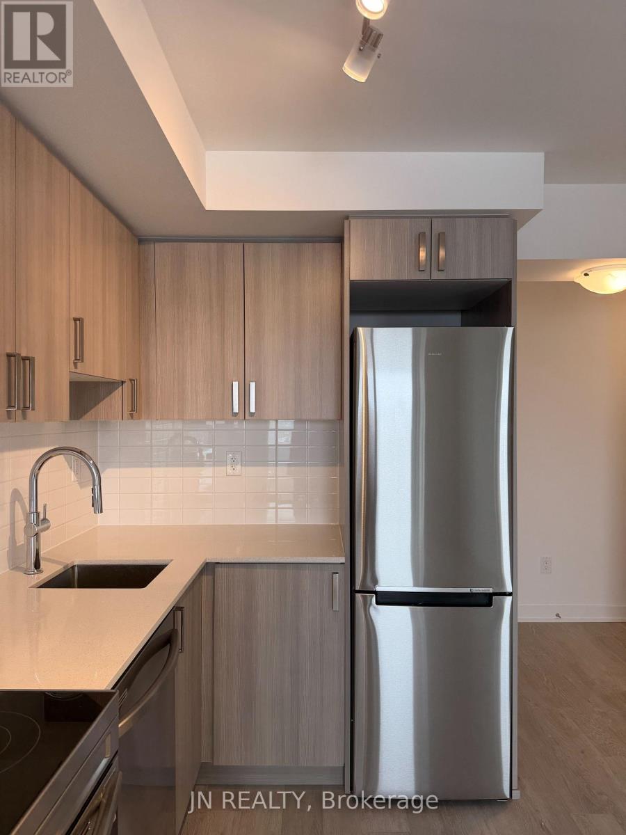 A modern kitchen with wooden cabinets and a stainless steel refrigerator.