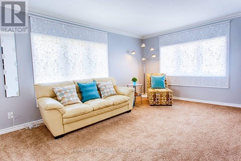 A living room with a tan couch and a small table with a plant on it.