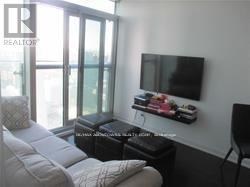 A living room with a white couch and a flat screen TV mounted on the wall.