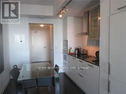 A kitchen with white cabinets and a glass table.