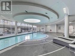 A large indoor swimming pool with a glass wall and a white ceiling.