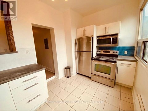 A kitchen with white cabinets and a stainless steel refrigerator.