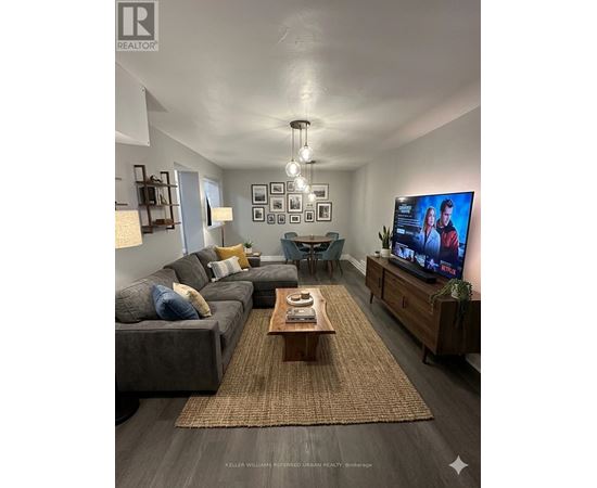 A living room with a grey couch, a coffee table, a flat screen TV and a rug.