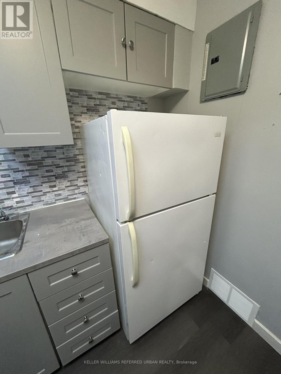 A white refrigerator in a kitchen with a sink and cabinets.
