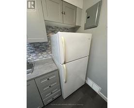 A white refrigerator in a kitchen with a sink and cabinets.