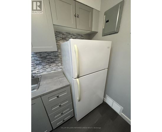 A white refrigerator in a kitchen with a sink and cabinets.
