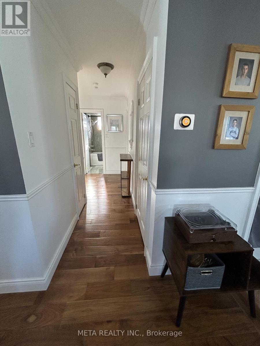 A spacious room with wooden flooring and white walls.
