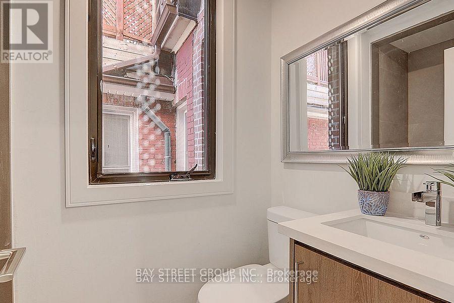 A bathroom with a sink, mirror, and a window showing a red building outside.